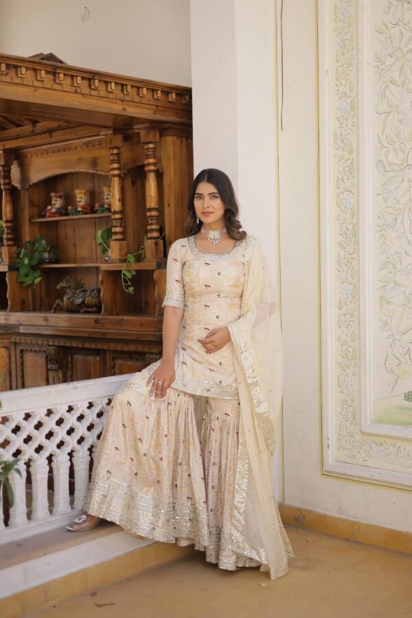 An elegant viscose jacquard gharara set featuring sequins and zari embroidery, a stylish round-neck kurti, and a Russian silk dupatta with embroidered lace. Available in Off-White, Rani-Pink, and Wine.