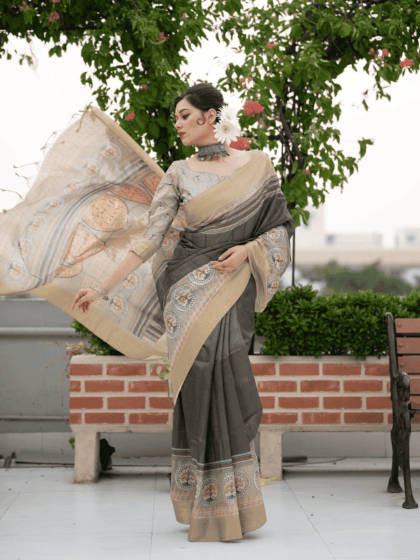 Tussar Print Soft Saree with a zari border, traditional Warli-printed pallu, a matching printed blouse, and fancy tassels for a graceful look.