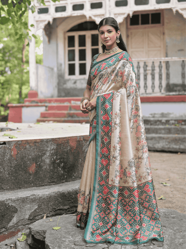 A soft Tussar silk saree adorned with a vibrant Patola print on the pallu and border, with a delicate floral jal pattern across the body. Includes a contrast blouse piece.