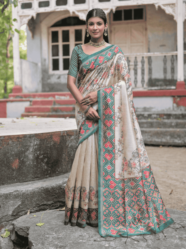 A soft Tussar silk saree adorned with a vibrant Patola print on the pallu and border, with a delicate floral jal pattern across the body. Includes a contrast blouse piece.