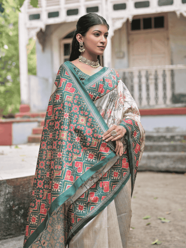 A soft Tussar silk saree adorned with a vibrant Patola print on the pallu and border, with a delicate floral jal pattern across the body. Includes a contrast blouse piece.