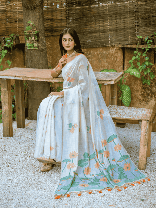 Exquisite soft silk saree with detailed floral weaving, a traditional Pichwai-style pallu, elegant tassels, and a stylish contrast blouse piece.