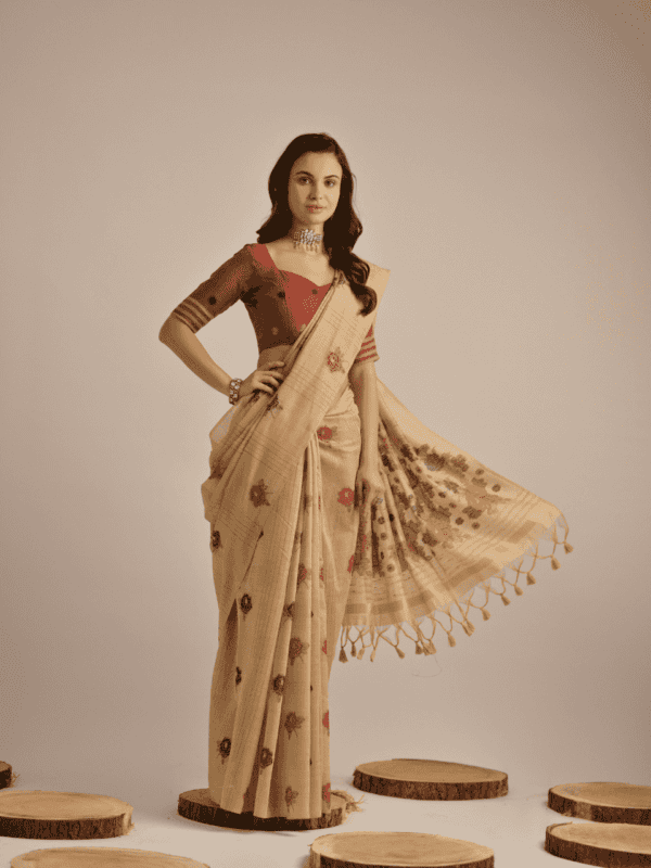 Traditional Muga Cotton saree with vibrant floral motif weaving, elegant buttas, and detailed lining, complemented by a contrast blouse and tassels.