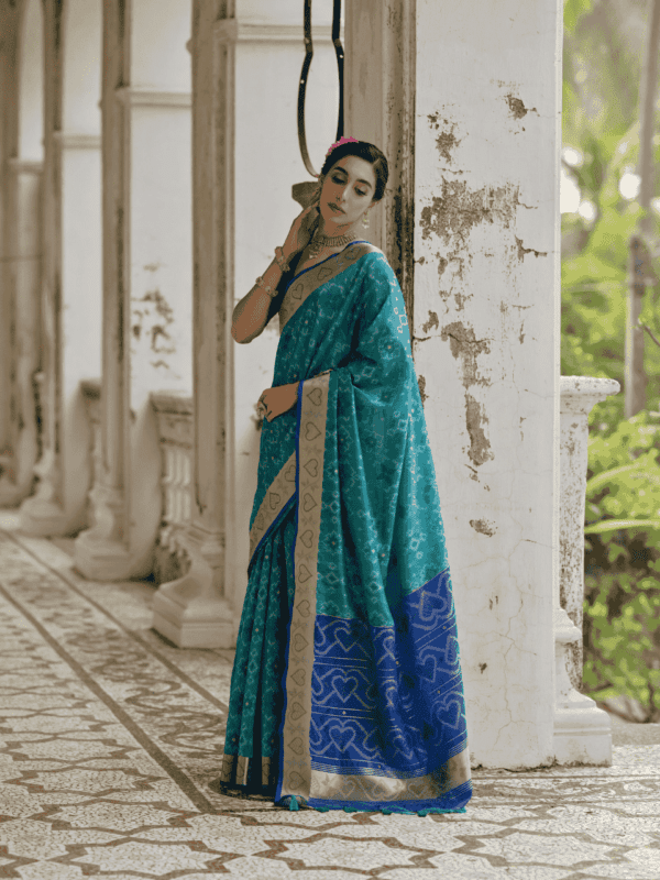 A beautifully woven Soft Desi Raw Silk saree with Pochampally Ikkat design, resham jal weaving, a zari border, and a classic traditional pallu with fancy tassels. Includes a contrast blouse piece.